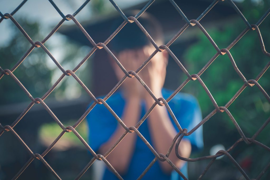 Niño llorando tras una valla metálica