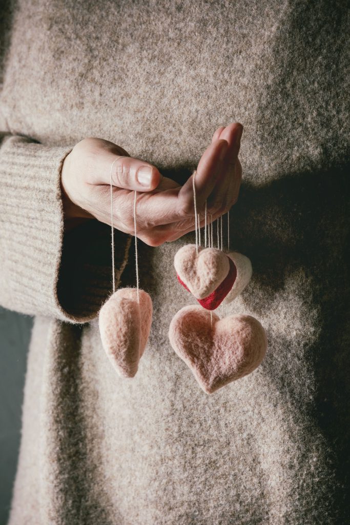 Manos de mujer sosteniendo corazones de fieltro